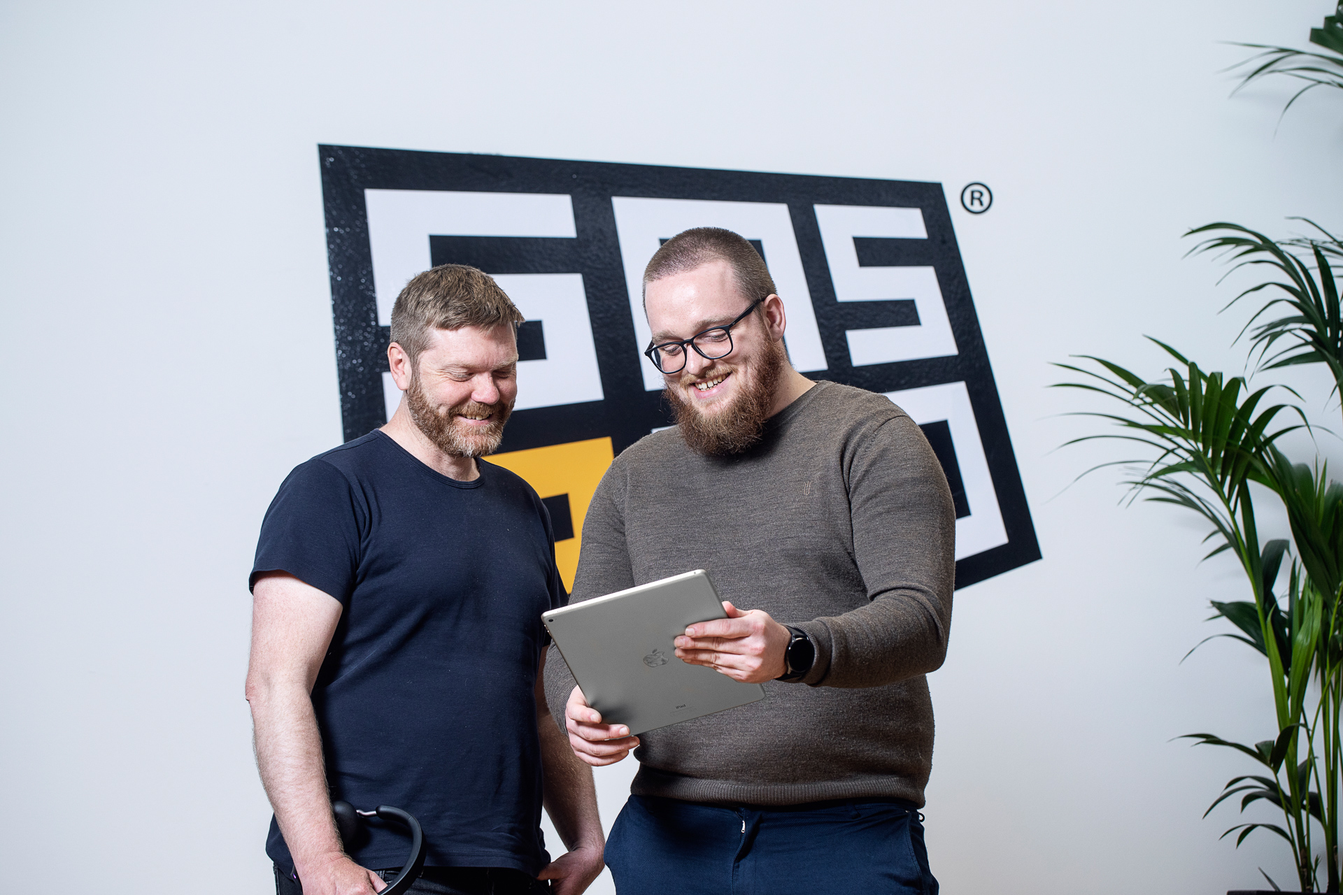 To kollegaer ser på en iPad foran SMS2GO-logoet